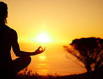 Rearview silhouette yoga woman meditating with legs crossed for outdoor practice in remote nature. Mindful person sitting alone and balancing for mental health at sunset. Serene and zen in lotus pose