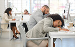 Two young mixed race call center agents sleeping at their desks while working in an office at work. Hispanic customer service workers taking a nap while working together