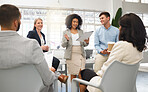 Group of five diverse businesspeople having a meeting in an office at work. Happy mixed race businesswoman reading a report in a workshop. Business professionals planning together