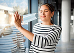 Young content mixed race businesswoman removing her mask while at work. One happy hispanic female businessperson taking off her mask protecting from virus while on a break at work