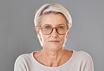 One mature caucasian woman wearing trendy brown prescription spectacles against a grey copyspace studio background. Senior female looking serious wearing reading glasses for better eyesight