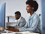 Happy young african american call centre telemarketing agent talking on a headset while working on computer in an office. Confident friendly female consultant operating helpdesk for customer service and sales support