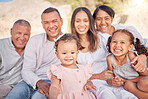 Portrait of a smiling mixed race family with little girls sitting  together at the beach. Adorable little kids bonding with their parents and grandparents while having a picnic at a park or garden
