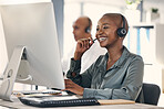 Happy young african american call centre telemarketing agent talking on a headset while working on a computer in an office. Confident friendly female consultant operating helpdesk for customer service and sales support