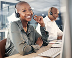 Portrait of happy young african american call centre telemarketing agent talking on a headset while working on a computer in an office. Confident friendly female consultant operating helpdesk for customer service and sales support