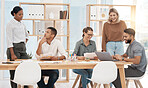 Group of diverse businesspeople brainstorming together around a table in an office boardroom. Team analysing research and marketing data while planning strategy in creative startup agency
