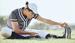 Full length of a baseball player sitting on a pitch and stretching before playing a game. Serious and focused athlete getting ready to play match on grass. Fit, active, sporty, athletic man warming up