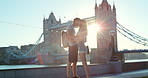 A couple kissing affectionately in front of Westminster bridge