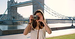 Cheerful young woman taking a photo with her camera on vacation in London