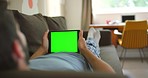 A digital tablet being used by a man relaxing on his couch in his lounge