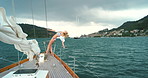 Carefree young woman in bikini leaning back on a yacht sailing around the Italian coast. Carefree woman enjoying herself sailing around Italy on a yacht on a cloudy day.