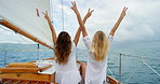 Carefree young women making peace signs during a cruise sitting on a boat. Two cheerful young friends making peace signs enjoying a cruise on the Italian ocean. Happy young women making peace signs
